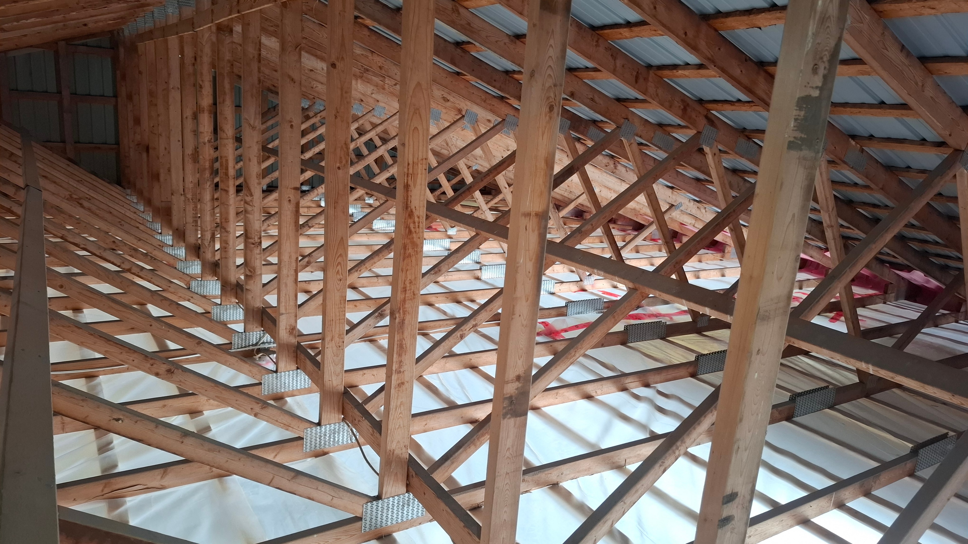 New construction attic trusses with poly vapour barrier laid — ready for cellulose installation
