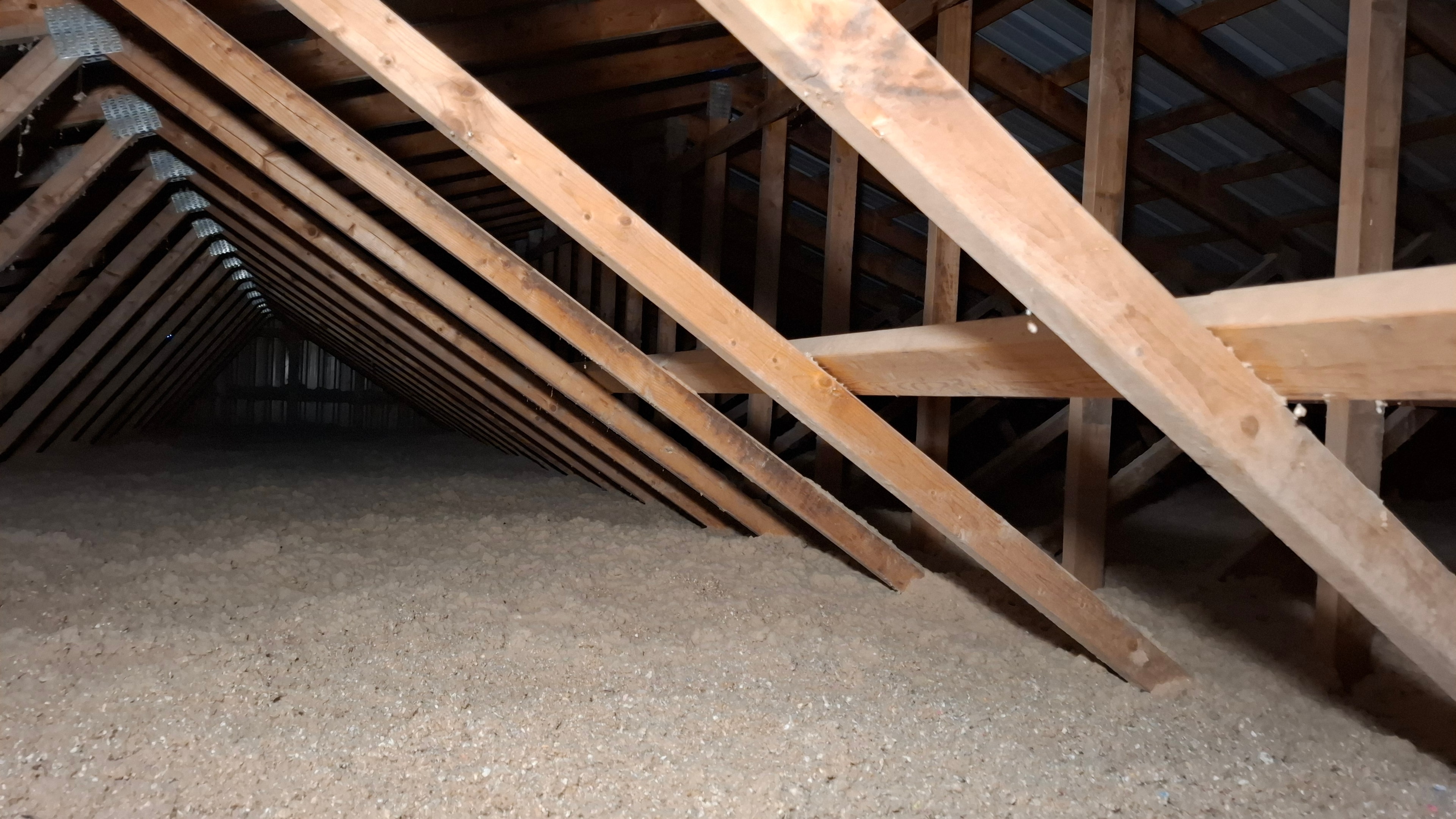 Close-up of completed blown-in cellulose between attic joists with depth gauge marker