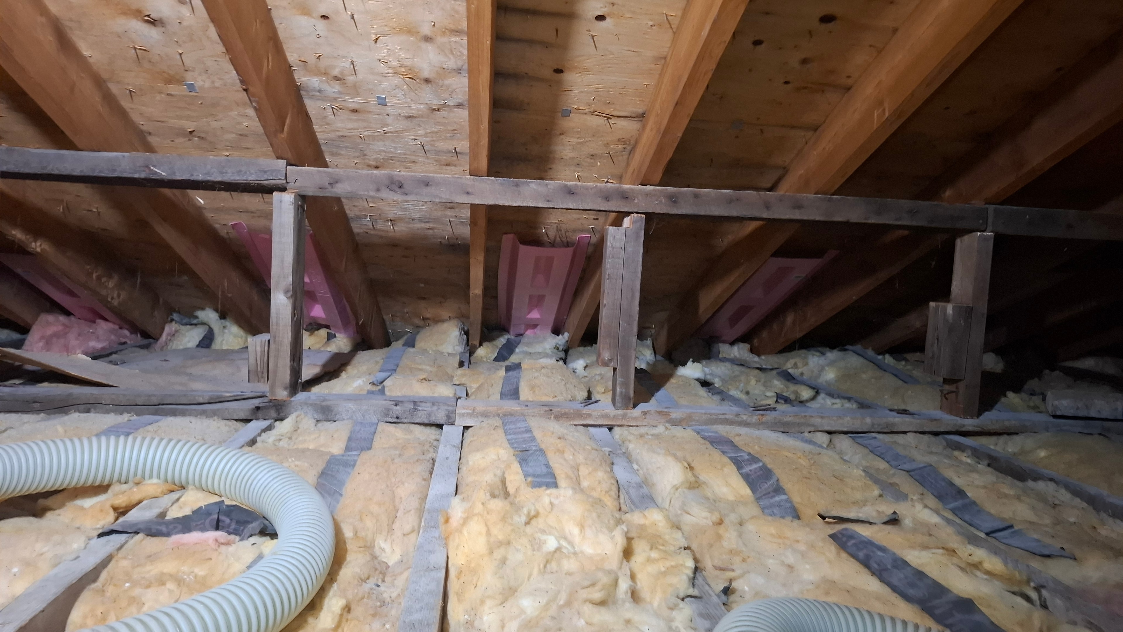 Blown-in cellulose installation in progress — cellulose hose covering attic floor