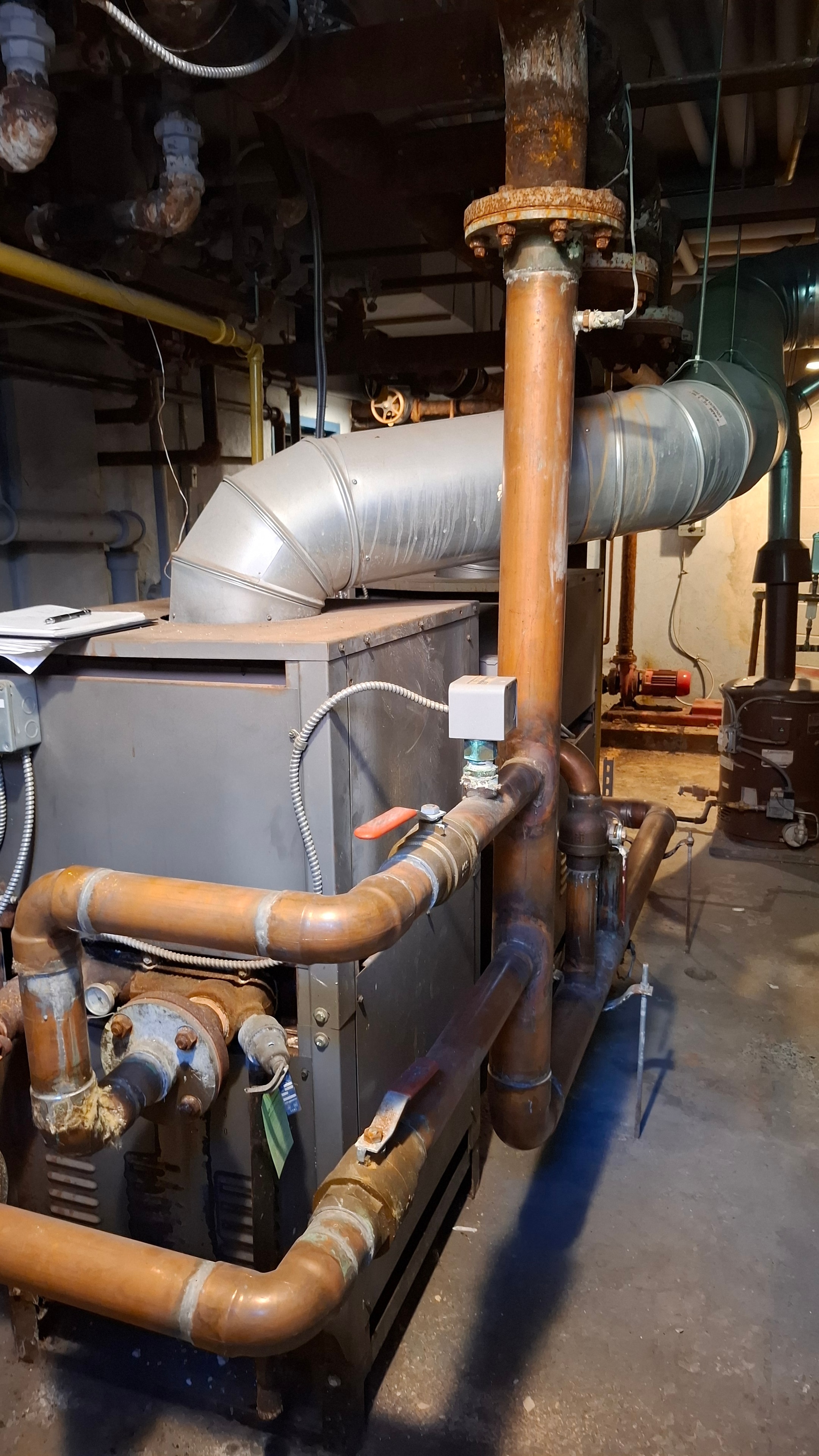 Before — bare uninsulated mechanical room piping around boiler and chiller unit