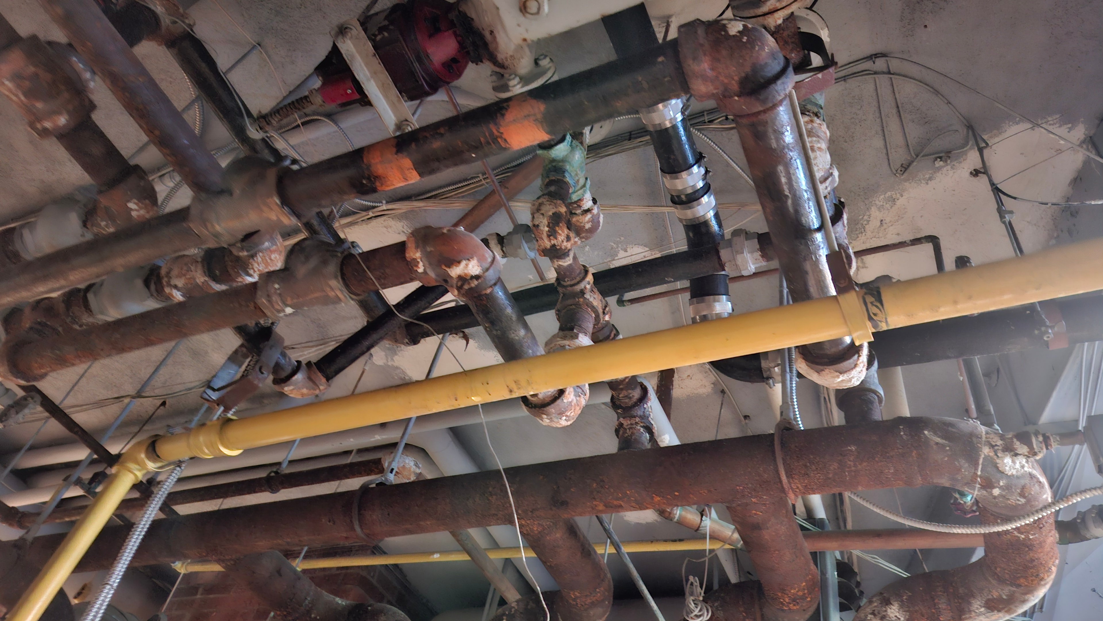 Before — overhead view of dense bare pipe runs with yellow gas line