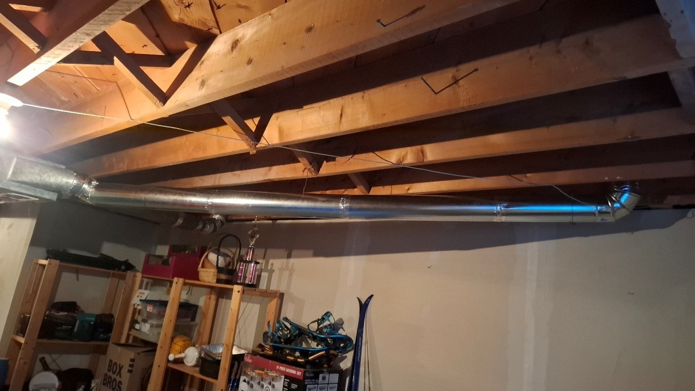 New round duct run across full span of basement ceiling after ACM abatement