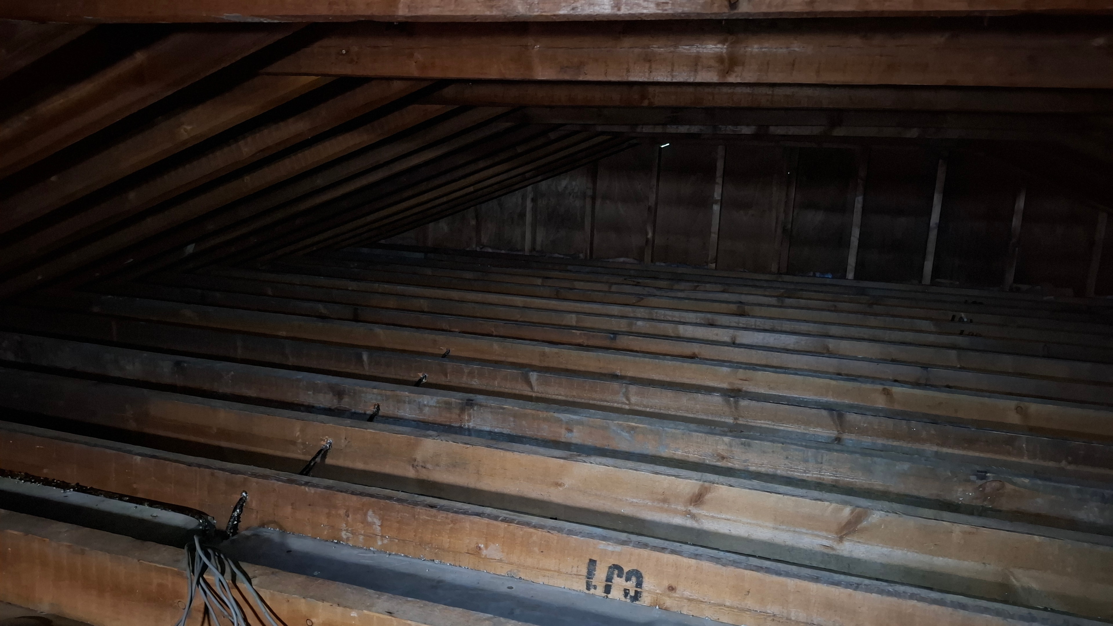 Attic after abatement — clean joist structure with all vermiculite removed
