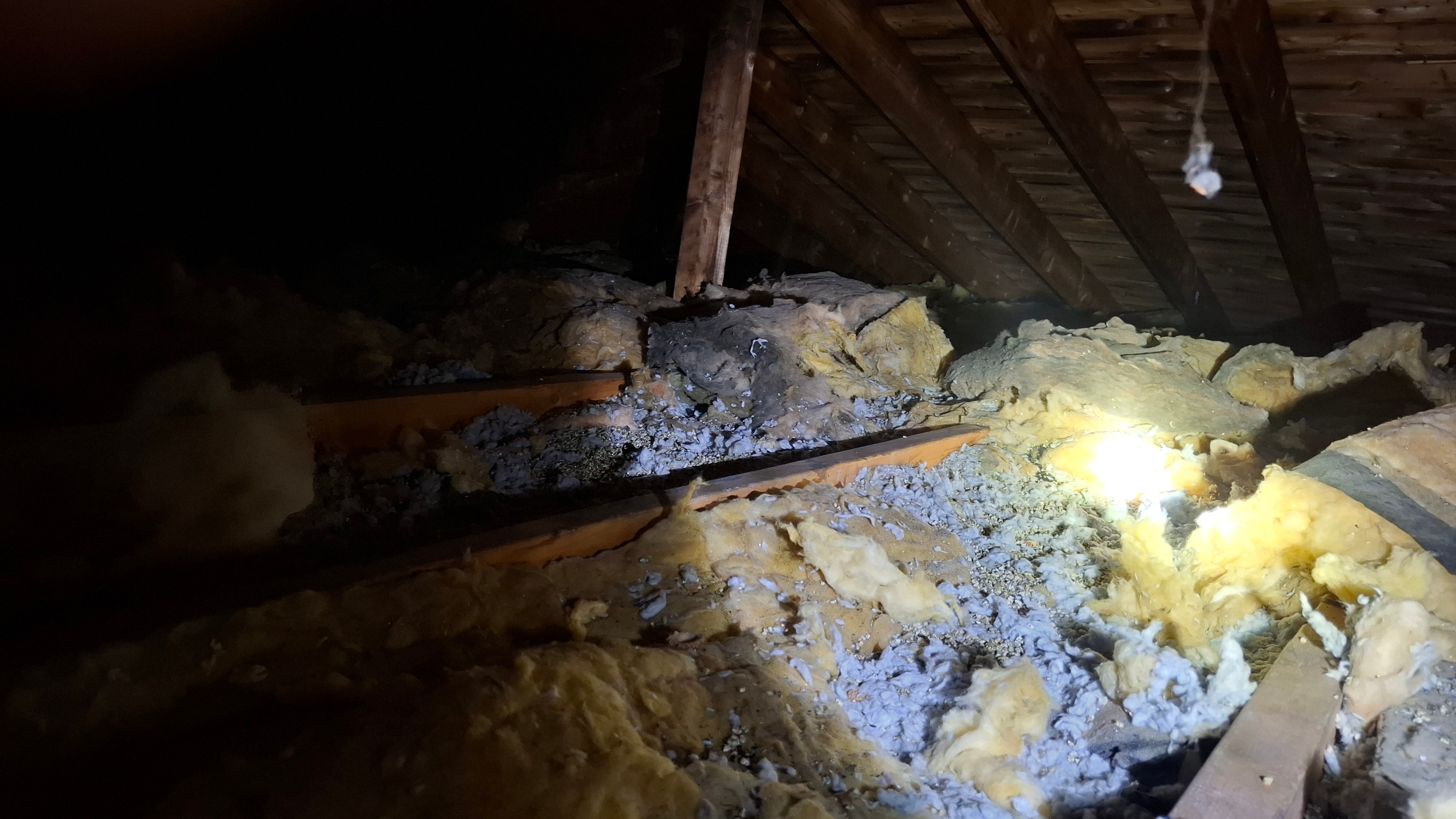 Existing attic conditions — vermiculite insulation beneath and around older fiberglass in Ottawa residential attic