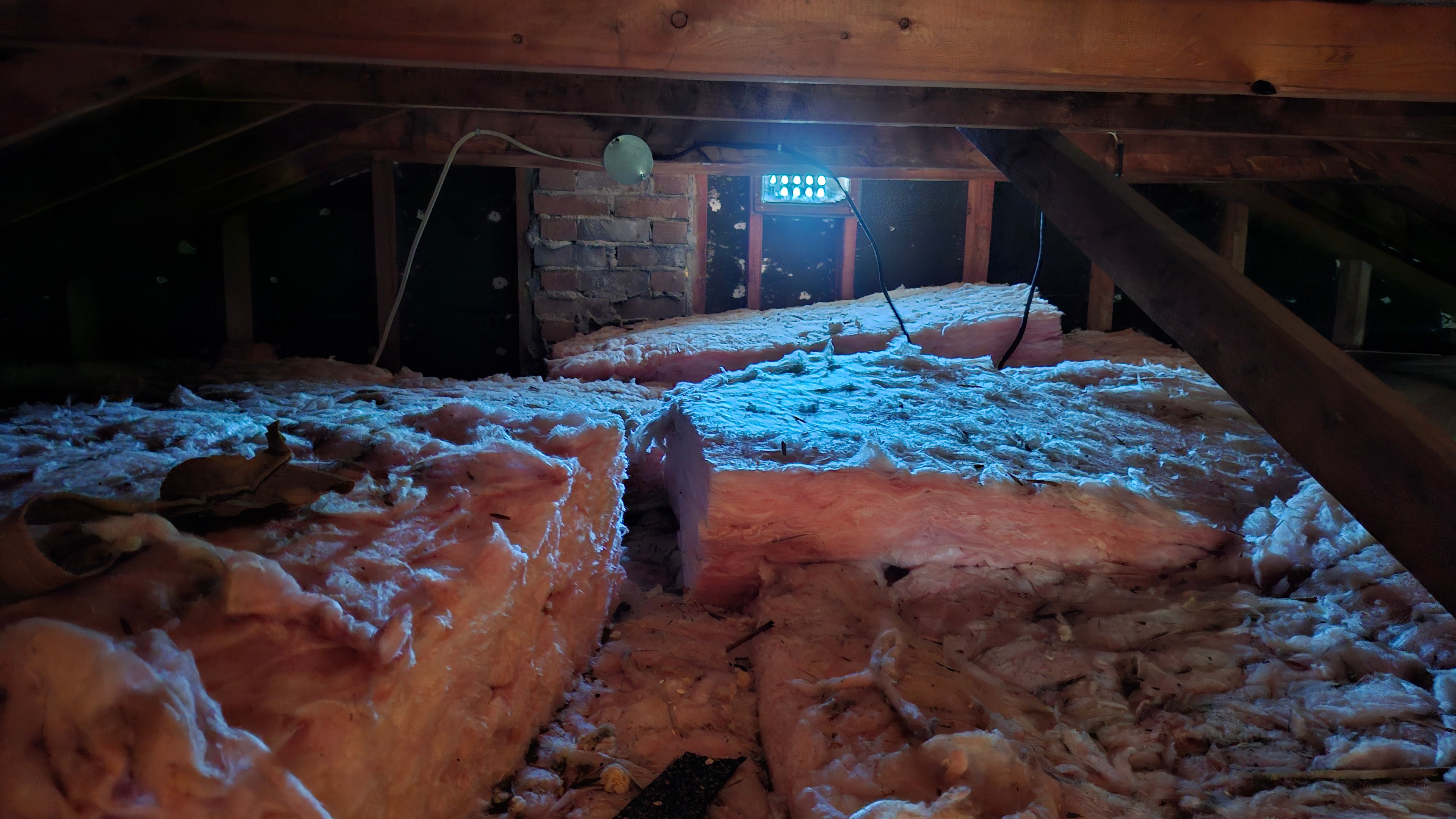 Residential attic interior showing existing insulation before vermiculite removal